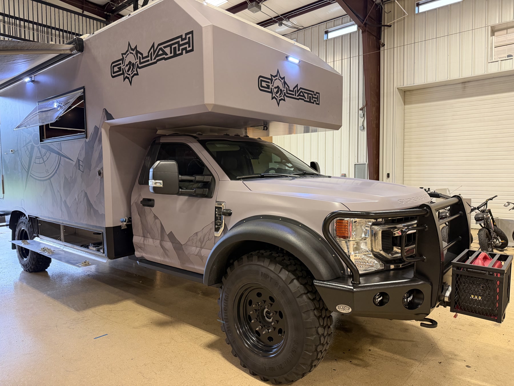 Goliath custom Ford F-550 adventure camper — matte gray mountain wrap, Buckstop bumper, GOLIATH badge